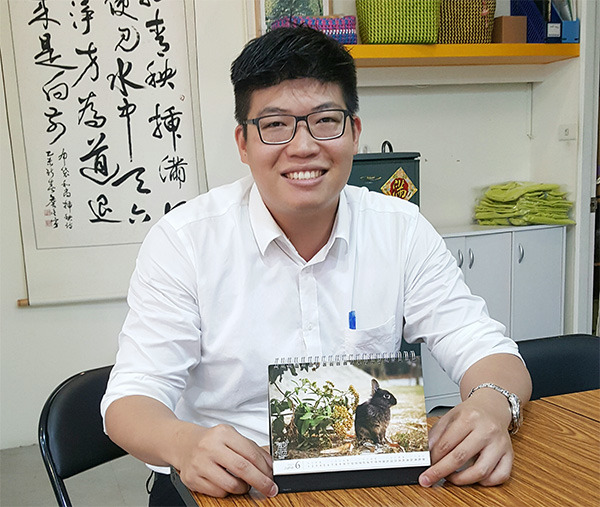 一心要打造寵物友善里的新世代里長詹晉鑒,手中這本兔子桌曆,也是里民的作品。 呂幼綸/攝