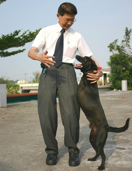 李朝全和他認養的流浪犬「暴龍」，前肢截肢只能靠後肢站立行走的「暴龍」，看到李處長馬上趨前撒嬌。蕭士塔/攝