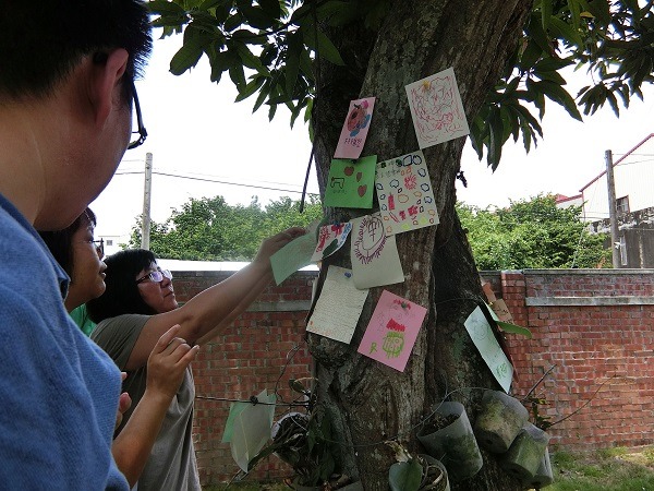 師生與神父製作祈福卡貼在樹幹上。 蕭士塔/攝