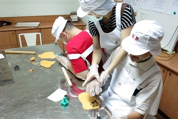 老師們耐心指導智青壓模，製作寵物零食。  蕭士塔/攝
