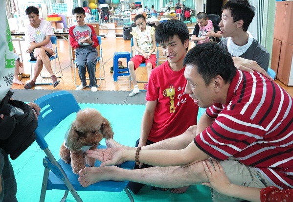 智青透過觸撫狗醫生Ruby，達到增進肢體伸展的功能。 蕭士塔/攝