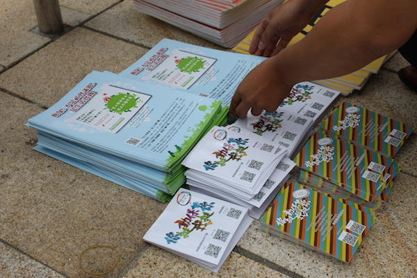 現場志工幫忙發送印有「毛孩是家人」、「你挺動保我挺你」的酷卡及傳單。   何宜/攝