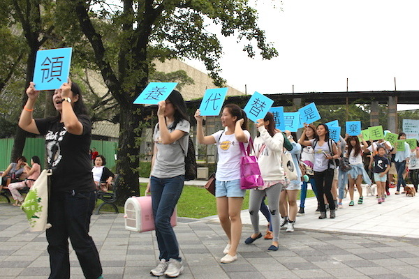 志工們手舉標語，在整點時分繞行花博公園呼喊「以領養代替購買」等標語。   何宜/攝