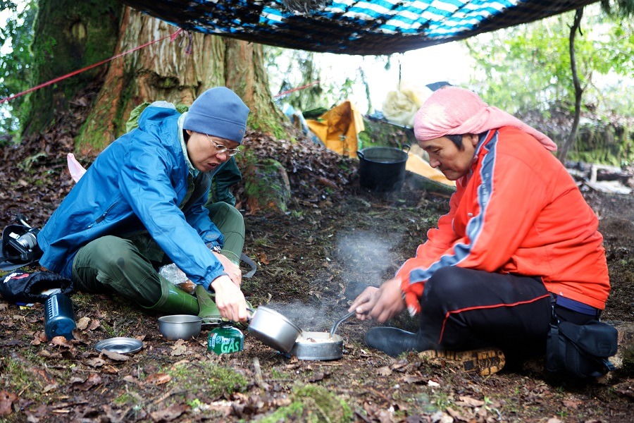 黑熊媽媽黃美秀和林淵源在防水布搭建的臨時休息地煮泡麵吃。　黑熊森林/提供