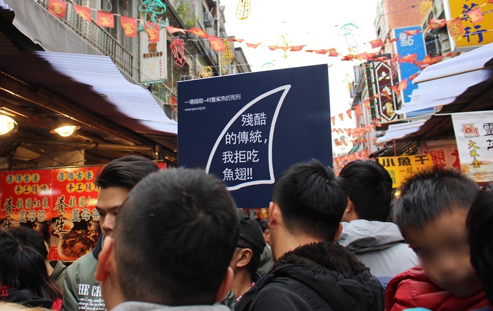 在擁擠的人群中，拒吃魚翅標語非常顯眼。　黃靖雅/攝