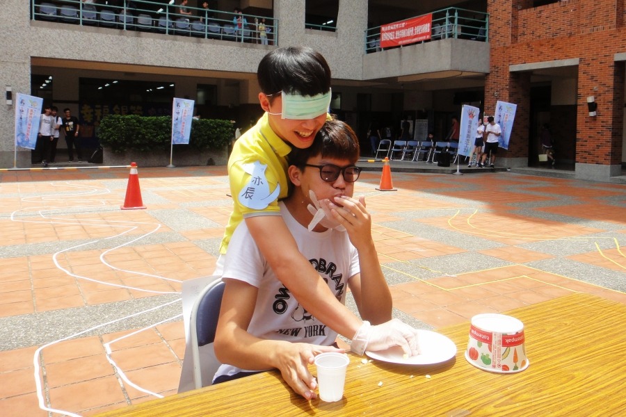 蒙眼學生一把將蛋糕塞進扮演導盲犬角色的學生口中。  江幸芸/攝