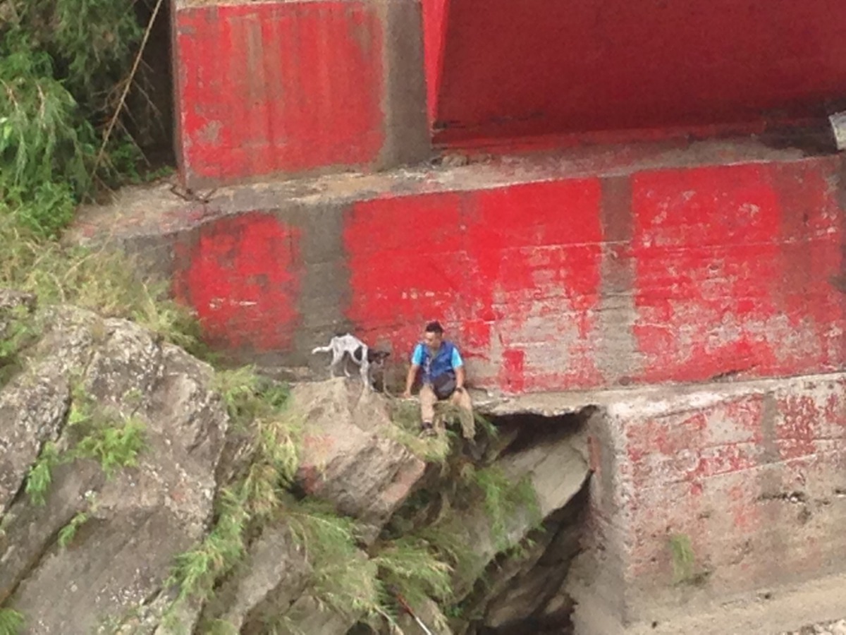 動物救援隊員余重諾陪受困狗狗坐在橋墩等待救援。新北市動保處/提供
