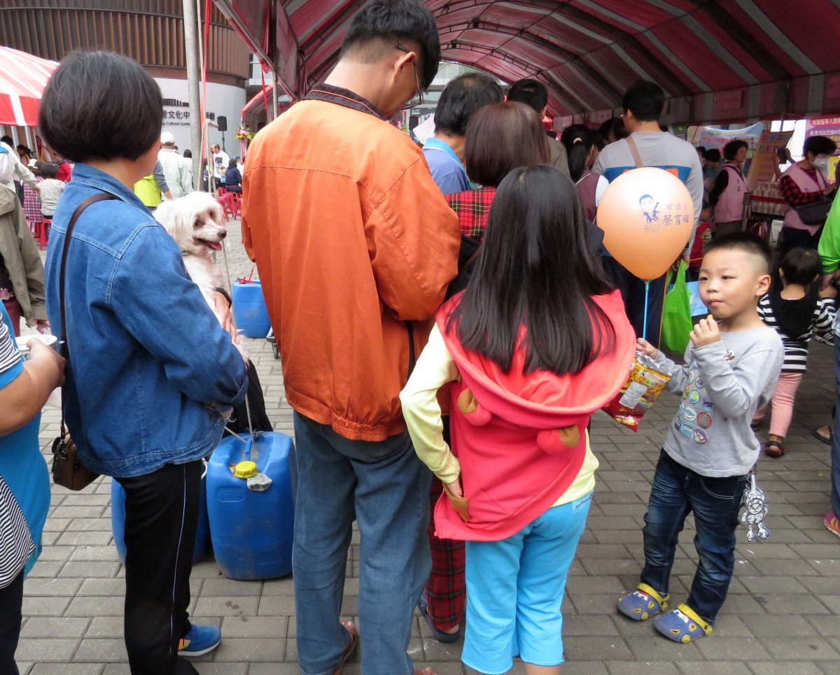 飼主抱著受犬排隊試吃美食。高維奇/攝