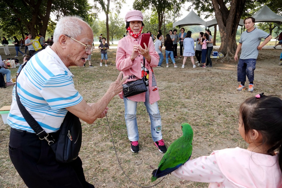 這位阿伯的鸚鵡不放飛,而是充當合照的模特兒。高維奇/攝