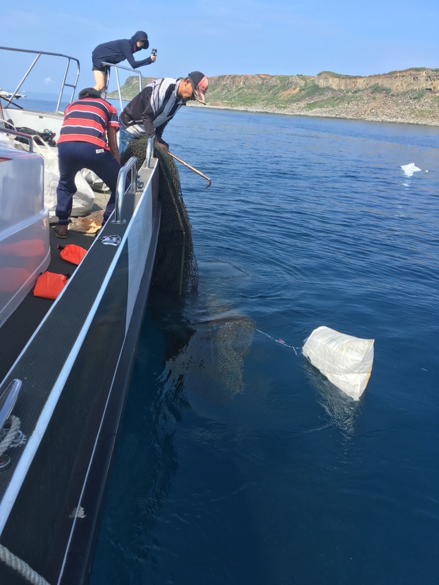 潛水人員於海底定位 再由船上人員協助撈起廢棄漁網漁具。國立高雄科技大學/提供