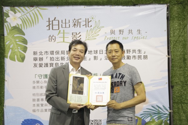 攝影展開幕活動由環保局長劉和然(左)頒發感謝狀予優選作品攝影者(右為何紀文)。新北市政府/提供
