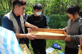 黎明向陽園朱祥安先生(左一)與同學在產蛋箱鋪上一層粗糠