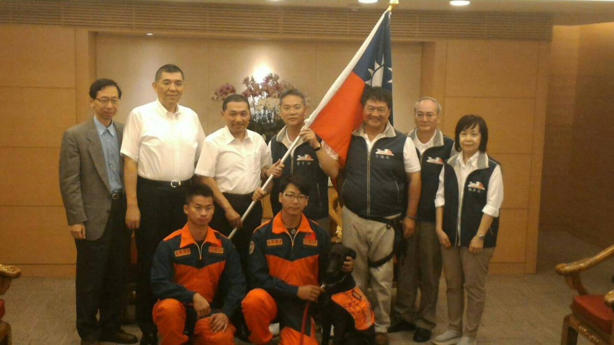 昨日新北市副市長侯友宜為搜救犬團隊主持授旗儀式，前排左起為控犬員凌國智、吳惟逸、搜救犬「風」。　台北市陪伴犬協會/提供