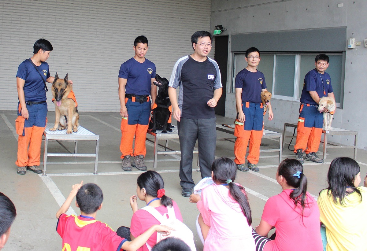 （由左至右）控犬員羅浩芳、凌國智、王駿程、黃榮宗帶領搜救犬無敵、爾文、小光、雪兒與小朋友互動。　李娉婷/攝
