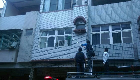 高雄市犬貓救援隊會同消防局，使用長梯救援卡在民宅窗台冷氣出風口的貓咪。　高雄市動保處/提供