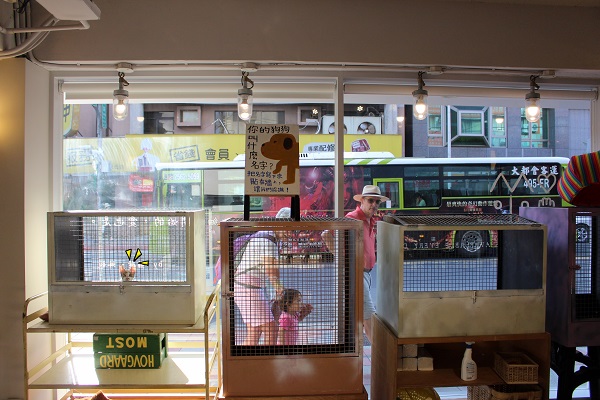 跑市場把待送養貓狗的籠子放在玻璃牆邊，民眾路過都能看見，有發現左邊籠子裡有隻貓咪嗎？牠剛做了壞事，得乖乖待在籠子裡。　江幸芸/攝