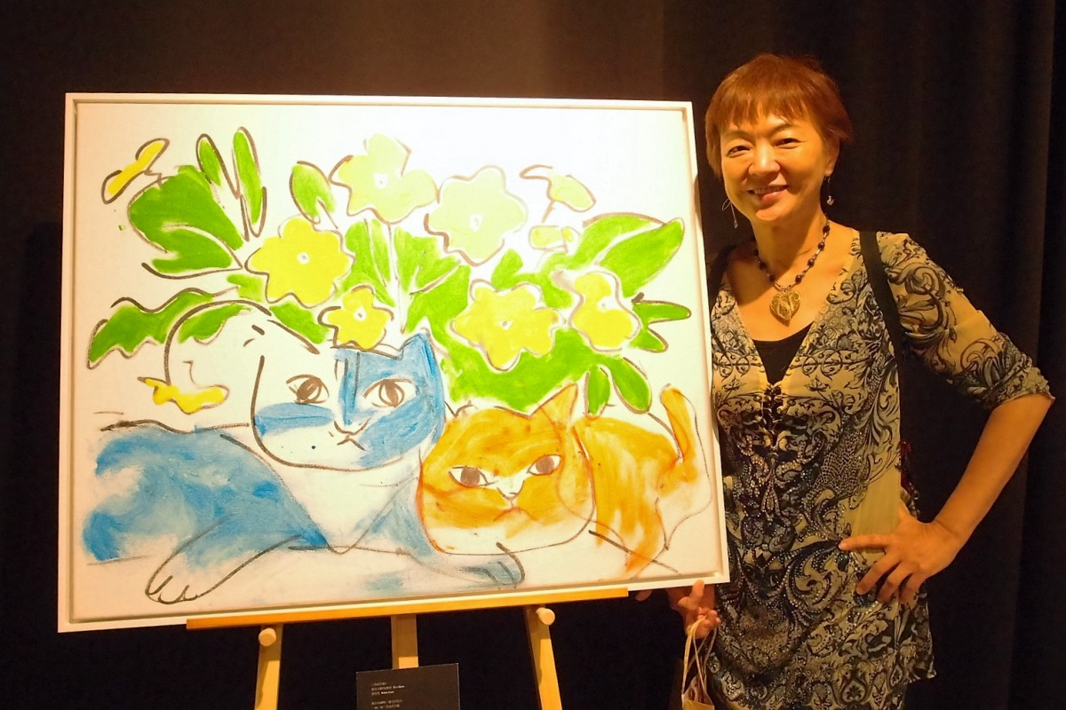 陳明芳女士與畫上留有愛貓Hola小爪痕的繪畫。李佳殷／攝