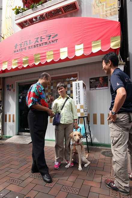 耐爾餐廳第二代老闆G.M.耐爾在門口迎接導盲犬使用者。 取自《THE PAGE》