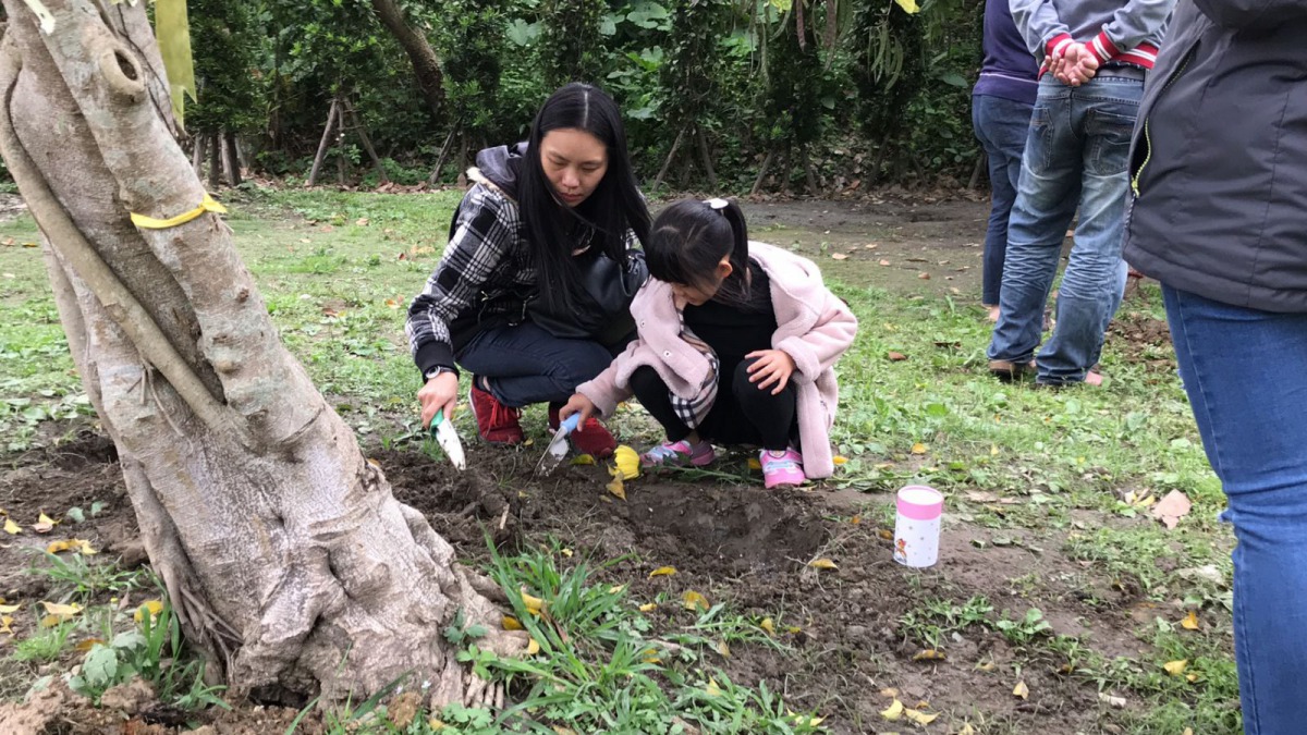 飼主參與樹葬,將毛孩的骨灰埋入土中。新北市動保處/提供
