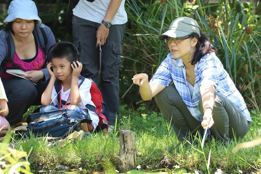 台灣聲景協會理事長范欽慧運用水下麥克風帶大家探索水下的聲音世界，小朋友戴上耳機仔細聆聽。台北市動保處/提供