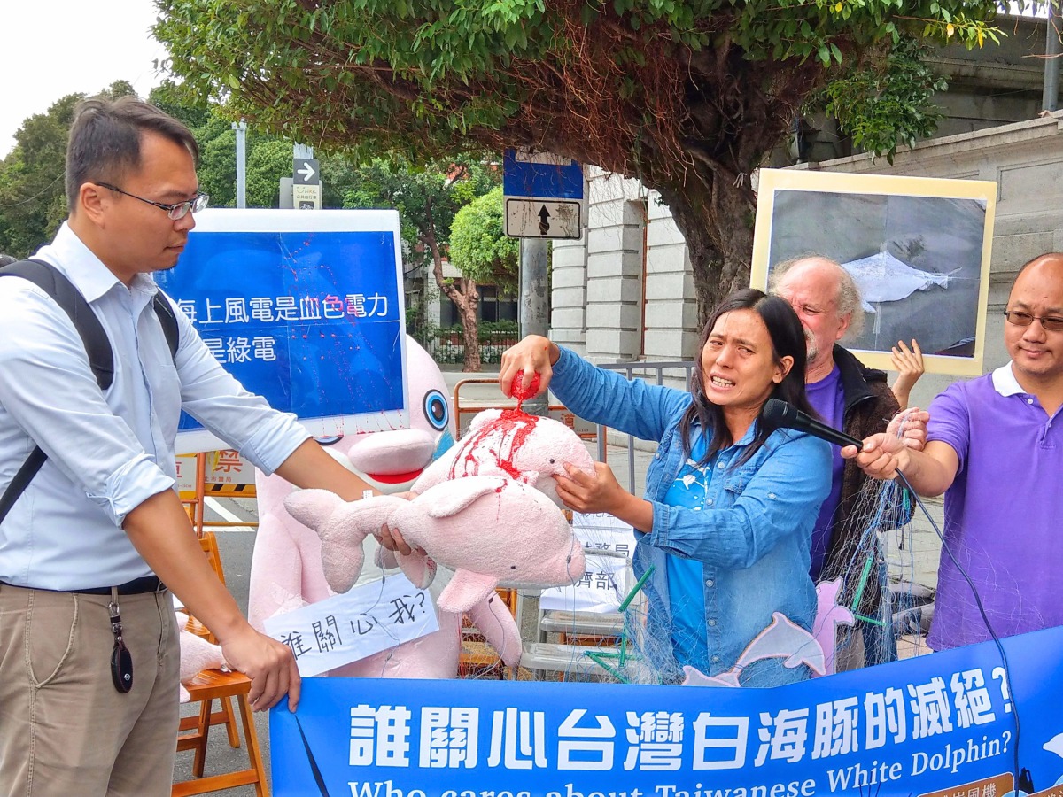 彰化縣環境保護聯盟總幹事施月英將紅色顏料倒在白海豚玩偶上，控訴開發案是血色電力。陳璽安/攝