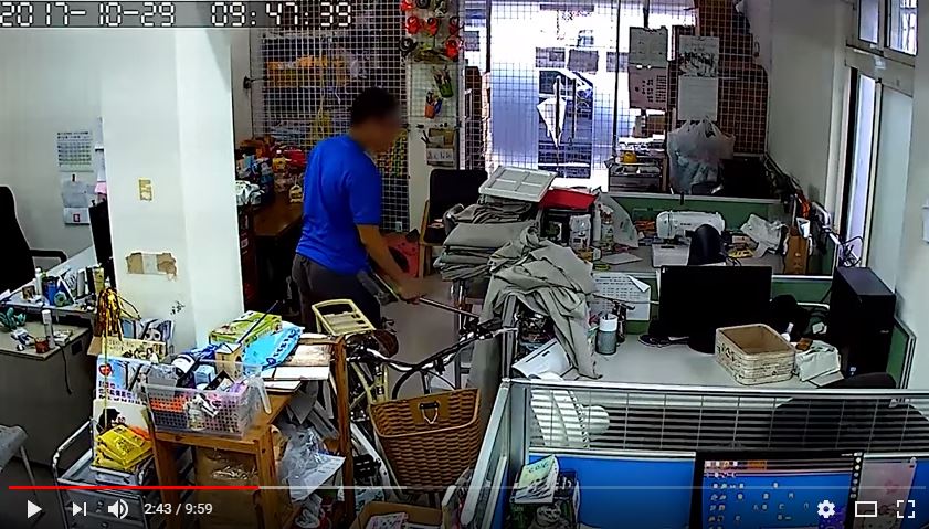 影片中，高姓員工一面親暱地問候威威，一面反握掃把，往威威躲藏的桌子底下伸。截取自https://youtu.be/3i9JI_-5fHc，臺北市支持流浪貓絕育計劃協會/提供