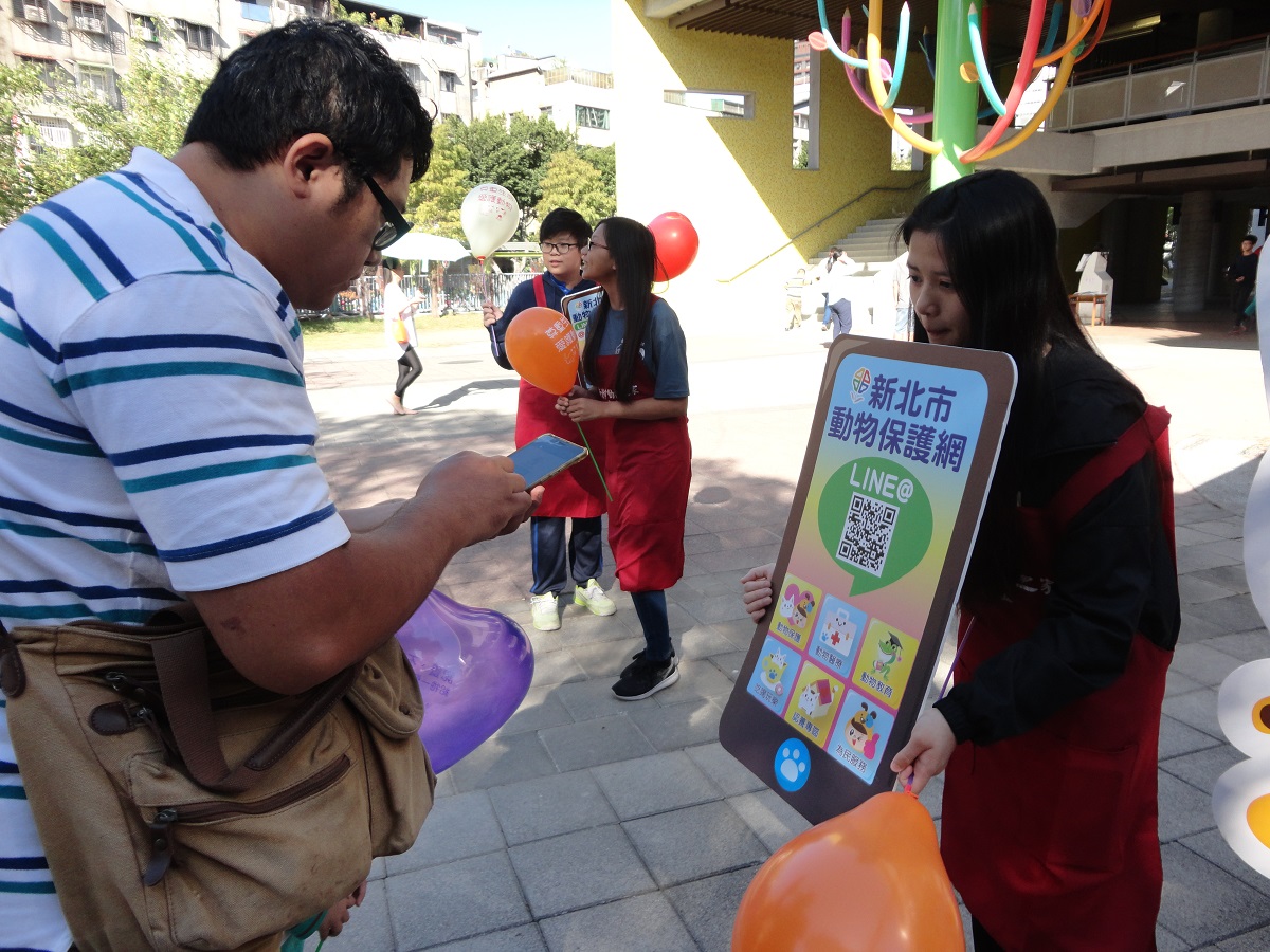 丹鳳高中學生協助新北市動保處到光興國小宣導動保教育，圖為丹鳳高中學生協助家長掃苗新北市動物保護網QR Code。新北市動保處/提供