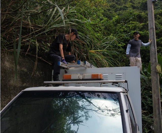 兩名動保員爬上車頂冒險救援受困山林的「小黑」。 新北市動保處/提供