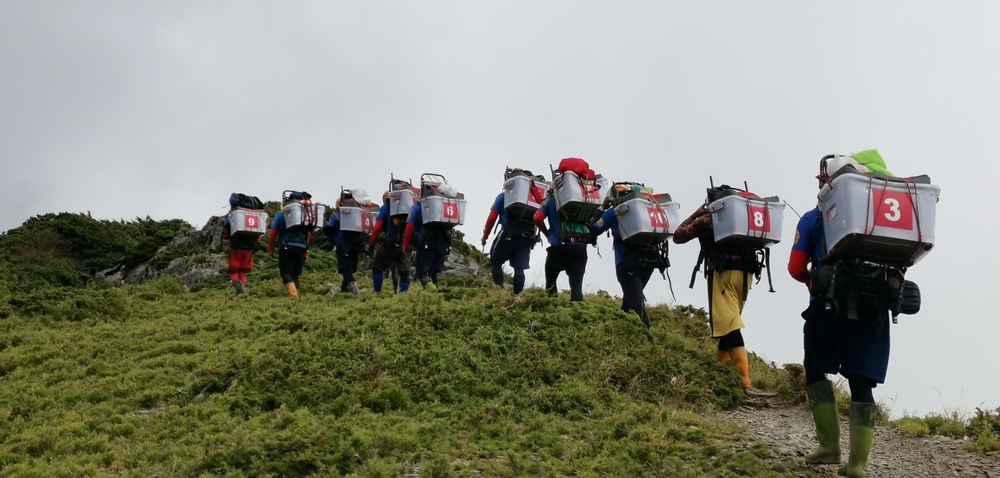 工作人員背著國寶魚,翻山越嶺至小嘆息灣進行放流工作。 雪霸處/提供