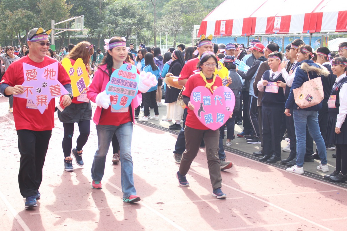 「為浪浪而跑」競走活動上,師生們拿著「愛牠不棄養」等動保標語。 姚崇仁/攝