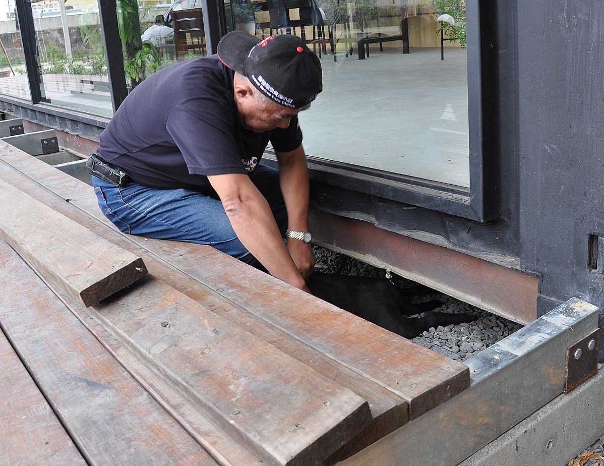 緊急救援小組大隊長倪兆成擠進狹小的木造砧板將狗狗救出來。台灣動物緊急救援小組/提供