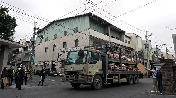 動物權推廣者在新北市肉品市場前,向送豬的貨車舉牌示意。蔡育琳/攝
